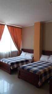 2 camas en un dormitorio con ventana en Hotel Dubái en Catamayo
