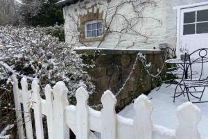 a white picket fence in the snow in front of a house at Coach House in Keighley