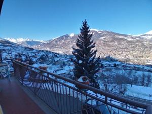 a christmas tree on a balcony with a snow covered mountain at Maison du Chasseur in Charvensod