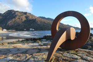 a sculpture on a beach with a mountain in the background at Apartamento A Cascada in Cee
