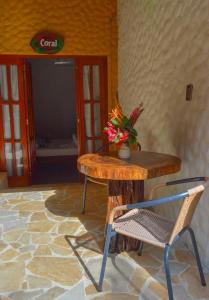 una mesa de madera y una silla con un jarrón de flores en Eco Hostal Kuima en El Zaino