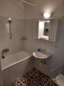 Baño blanco con bañera y lavamanos en Eszterlánc Apartman Eger, en Eger