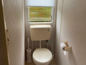 a small bathroom with a toilet and a window at Inviting Mobile Home in Auw near Lake, City Centre in Auw