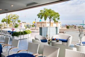 un restaurante con sillas blancas y mesas en un balcón en Hotel Foschi-Peninsula, en Bellaria-Igea Marina