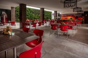 um restaurante com cadeiras e mesas vermelhas e um grande ecrã em Hotel San Martin Popayan em Popayán