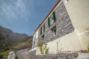 a stone building with green windows on a mountain at Green Valley House Madeira in Ribeira Brava