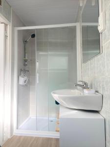 a white bathroom with a sink and a shower at L’Abri Côtier in Le Tréport