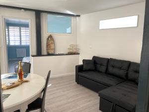 a living room with a black couch and a table at L’Abri Côtier in Le Tréport