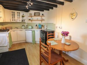 una cocina con una mesa de madera y una mesa pequeña con flores. en Northgate Cottage en Holywell