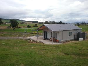 a small white building with a grass field at Meander Country Cabins & Vans in Meander