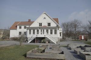 een groot wit huis met een veranda en een tuin bij Villa Bro in Brastad