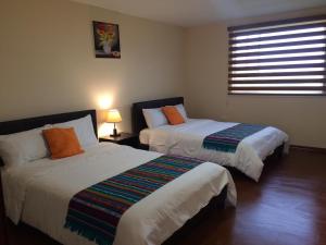 a bedroom with two beds and a window at Las Hortensia's Casa De Huespedes in Tababela