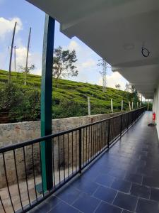 a walkway with a fence and a hill in the background at Flamingo's Nuwara Eliya in Nuwara Eliya