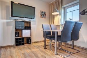 ein Esszimmer mit Tisch und Stühlen und einem Fernseher in der Unterkunft Der Landhof Windflüchter in Stolpe auf Usedom