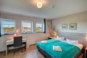 ein Hotelzimmer mit einem Bett, einem Schreibtisch und Fenstern in der Unterkunft Der Landhof Windflüchter in Stolpe auf Usedom