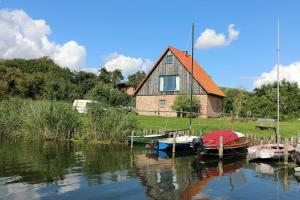 ein Haus mit vor dem Wasser angedockten Booten in der Unterkunft Der Landhof Windflüchter in Stolpe auf Usedom