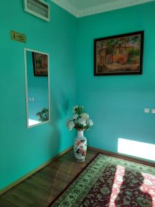 a room with blue walls and a vase with flowers in it at Hotel ВаYan in Shymkent