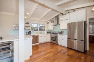 een keuken met witte kasten en een roestvrijstalen koelkast bij Ocean & Mountain View Home - Walk to Trails Beach Family Activities in Montara