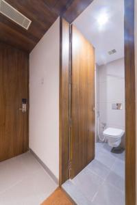 ein Badezimmer mit einem WC und einer Holztür in der Unterkunft Sky Ridge in Vijayawāda