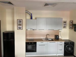 a kitchen with white cabinets and a sink and a dishwasher at Sofia Family House - Free Parking in Sofia