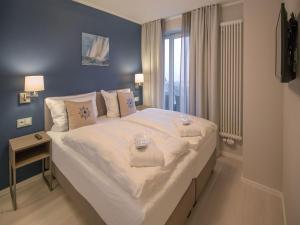 ein großes weißes Bett in einem Zimmer mit Fenster in der Unterkunft Dünenresidenz Prora - Skysuite mit freiem Meerblick, Dachterrasse und Balkon NP-502 in Binz