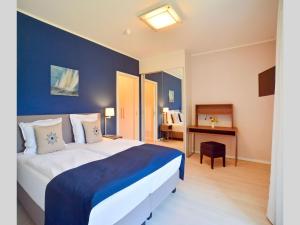 ein Hotelzimmer mit einem großen Bett und einem Schreibtisch in der Unterkunft Dünenresidenz Prora - Ferienwohnung mit Meerblick und 1 Schlafzimmer und Terrasse NP-704 in Binz