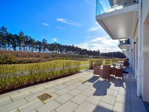 eine Terrasse mit einem Tisch und Stühlen auf einem Haus in der Unterkunft Dünenresidenz Prora - Ferienwohnung mit Meerblick und 1 Schlafzimmer und Terrasse NP-704 in Binz