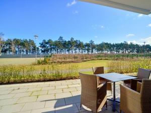 eine Terrasse mit einem Tisch, Stühlen und einem Feld in der Unterkunft Dünenresidenz Prora - Ferienwohnung mit Meerblick und 1 Schlafzimmer und Terrasse NP-704 in Binz
