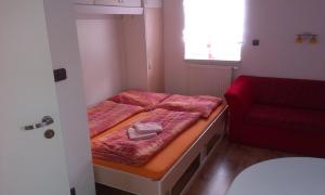 Habitación pequeña con cama y silla roja. en Studia Relax, en Železná Ruda