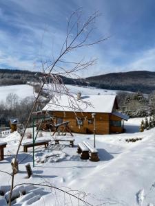 a log cabin with snow on the ground at Kiczurka Bieszczady in Baligród