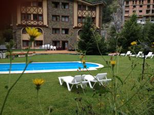 un complejo con piscina, sillas y un edificio en Hotel Xalet Verdú en Arinsal