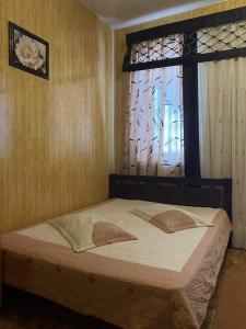 sypialnia z łóżkiem z oknem i narzutą w obiekcie Отель Ритм w mieście Winnica