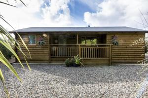 a log cabin with a porch and a deck at Fern Lodge - 2 Bedroom Log Cabin - Saint Florence - Tenby in Saint Florence