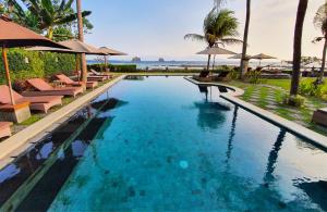a large swimming pool with chairs and umbrellas at Hotel Genggong in Candidasa