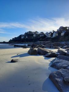 une plage de sable avec des rochers et des maisons sur une colline dans l'établissement Appartement plage de Trestraou 45m2, à Perros-Guirec