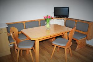a wooden table with chairs and a vase of flowers on it at Filzmoos Appartements in Filzmoos +8 photos