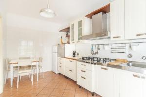 a kitchen with white cabinets and a small table at EUR Luminous and Large Family Terrace Apartment in Rome