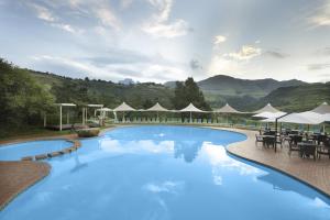 ein großer Pool mit Tischen und Sonnenschirmen in der Unterkunft Drakensberg Sun Resort in Winterton
