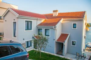 a white house with an orange roof next to the water at Beach Apartments in Tivat