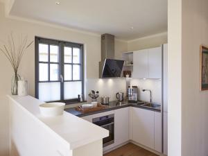 德蘭斯克的住宿－Reetland am Meer - Premium Reetdachvilla mit 3 Schlafzimmern, Sauna und Kamin E16，厨房配有白色橱柜和窗户。