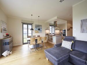 a living room with a blue couch and a kitchen at Reetland am Meer - Premium Reetdachvilla mit 3 Schlafzimmern, Sauna und Kamin E19 in Dranske