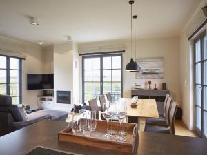 una sala de estar con una mesa con copas de vino. en Reetland am Meer - Premium Reetdachvilla mit 3 Schlafzimmern, Sauna und Kamin E19, en Dranske