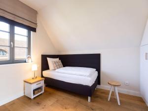 ein kleines Schlafzimmer mit einem Bett und einem Fenster in der Unterkunft Reetland am Meer - Premium Reetdachvilla mit 3 Schlafzimmern, Sauna und Kamin E08 in Dranske