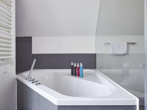a large white tub in a bathroom with a bath tub at Reetland am Meer - Luxus Reetdachvilla mit 3 Schlafzimmern, Sauna und Kamin E20 in Dranske +10 photos