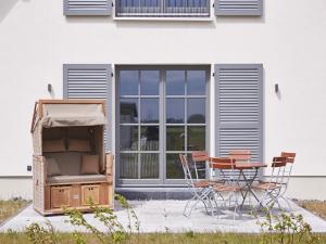 a patio with a table and chairs in front of a house at Reetland am Meer - Premium Reetdachvilla mit 3 Schlafzimmern, Sauna und Kamin E24 in Dranske