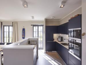 cocina con paredes azules y encimera blanca en Reetland am Meer - Luxus Reetdachvilla mit 3 Schlafzimmern, Sauna und Kamin E27, en Dranske