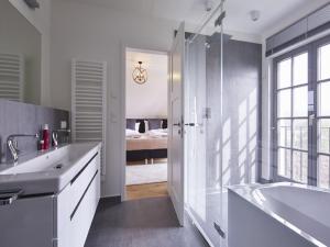 a bathroom with a sink and a tub and a bedroom at Reetland am Meer - Luxus Reetdachvilla mit 3 Schlafzimmern, Sauna und Kamin E27 in Dranske +9 photos