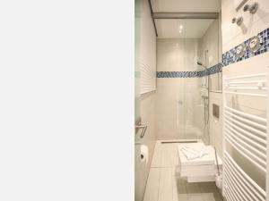 a white bathroom with a shower and a toilet at Strandvillen Binz - Ferienwohnung mit Meerblick, 2 Schlafzimmern und Balkon SV-008 in Binz +5 photos