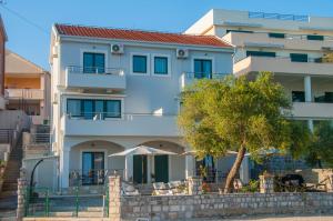 a white building with a tree in front of it at Beach Apartments in Tivat