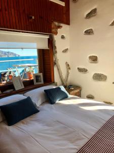 モンテロッソ・アル・マーレにあるLa Casa Del Doganiereのベッドルーム1室(ベッド2台付)、壁に岩を貼った窓が備わります。